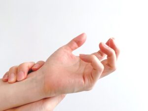 指の付け根を押さえる手（ばね指の痛み）